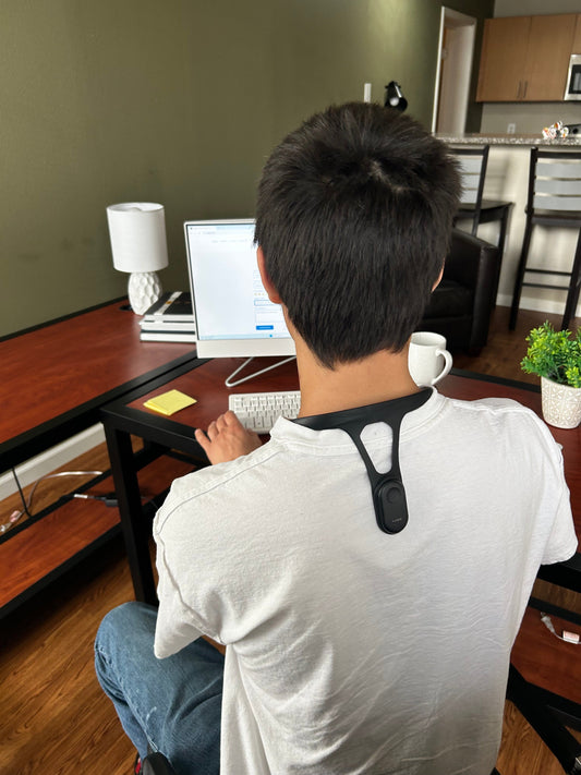 image male of him sitting straight with the verulex smart posture trainer on his upper back in office setting.