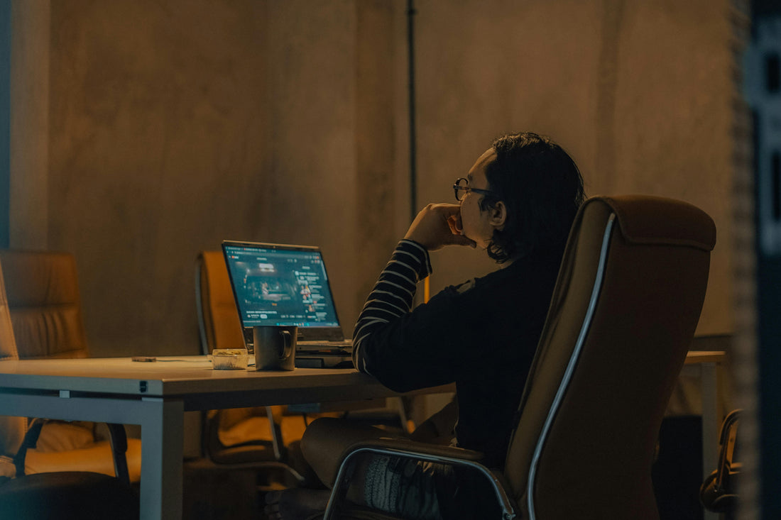 Person sitting at a desk working on a laptop, showing a typical seated posture during desk work.